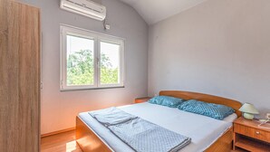Et soveværelse med seng, et natbord, en lampe og en aircondition.