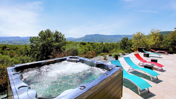 A hot tub with a scenic view of mountains and greenery.