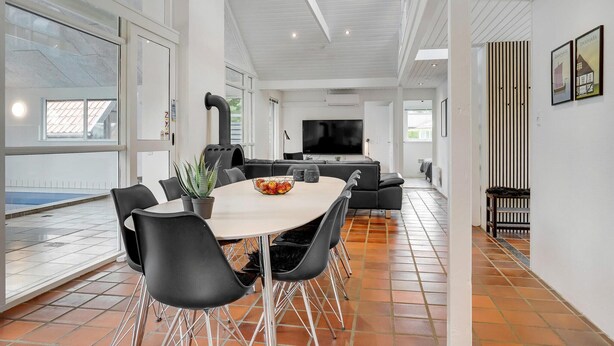 Een moderne woonkamer met een eetgedeelte, grote ramen en een open haard.