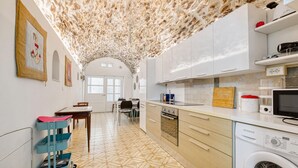 Une cuisine moderne avec des meubles blancs, un lave-linge et un coin repas comprenant une table et des chaises.