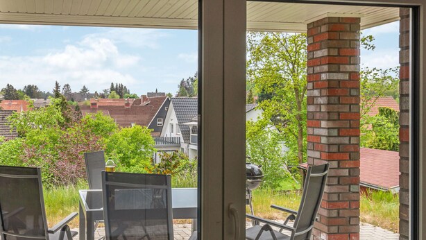 A patio with a table and chairs, a brick pillar, and a view of houses and trees. - Amazing home in Bleckede with WiFi (Bleckede)