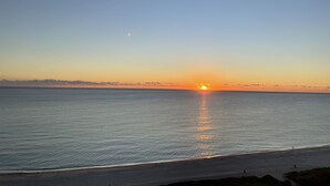 Solnedgang over et roligt hav med en klar himmel.