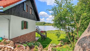 Uma casa com fachada de madeira, telhado vermelho e vista para um lago.
