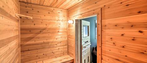 A wooden sauna room with benches and a door leading to another room.