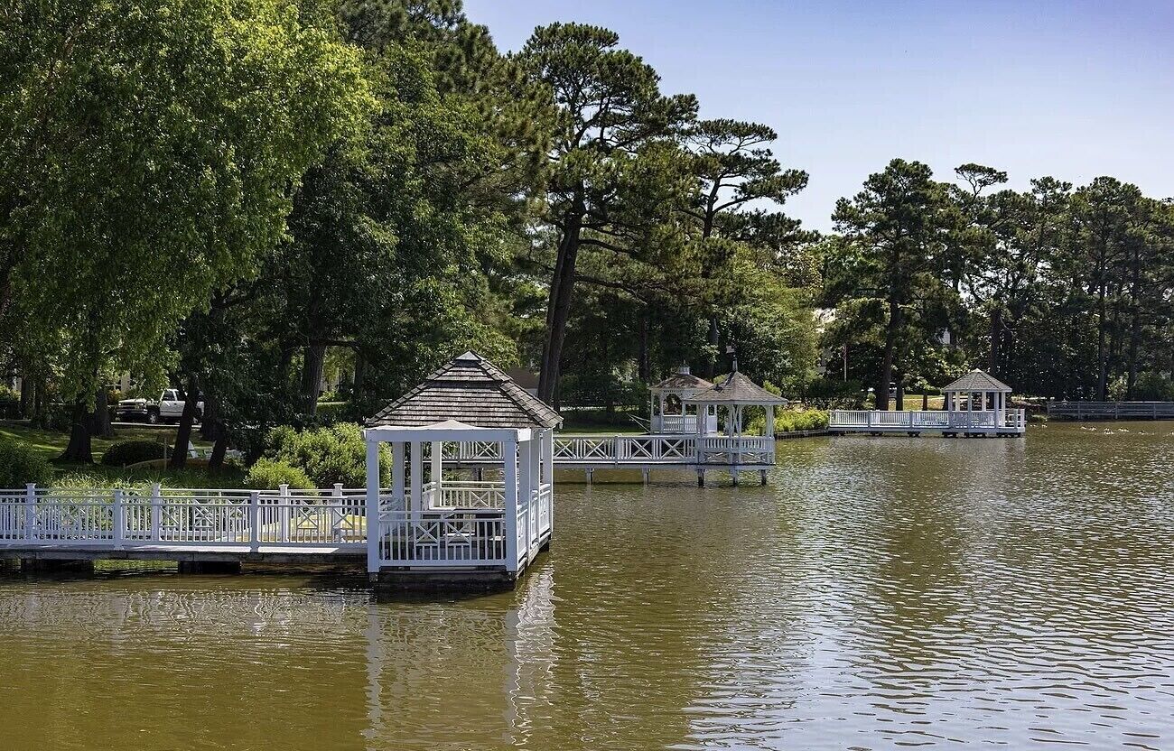 Uma estrutura em estilo de gazebo sobre um lago, rodeada por árvores.