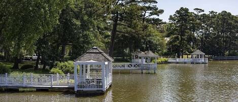 Uma estrutura em estilo de gazebo sobre um lago, rodeada por árvores.