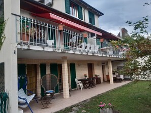 Un bâtiment à deux étages doté d’un balcon, d’un espace extérieur aménagé pour s’asseoir et d’un jardin.