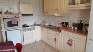 Kompakti keittiö, jossa on valkoiset kaapit, sisäänrakennettu uuni, pesuallas ja kahvinkeitin.