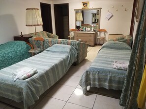 Ein Zimmer mit zwei Einzelbetten, einem kleinen Tisch mit Stuhl, einem Schminktisch und einem Spiegel.