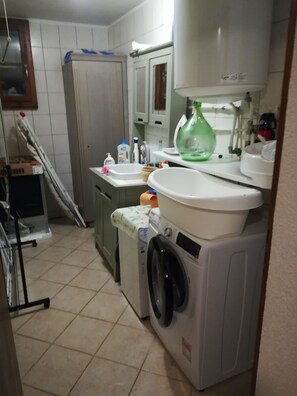 Eine kleine Küche mit Waschmaschine, Spüle und Schränken.