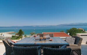 Eine Terrasse mit Korbmöbeln und Blick auf die Küste.
