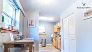 A modern kitchen with wooden cabinets, a dining table, and a view of the city. - Luxe King Studio w/ Amazing View ~ Free Parking & WiFi (Memphis)