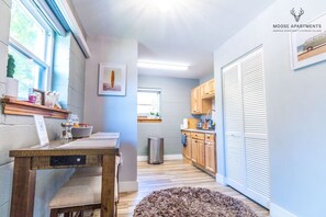 A modern kitchen with wooden cabinets, a dining table, and a view of the city. - Luxe King Studio w/ Amazing View ~ Free Parking & WiFi (Memphis)