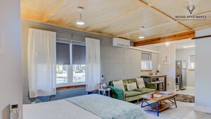 A modern bedroom with a bed, a green sofa, a small table, and a kitchenette in the background. - Luxe King Studio w/ Amazing View ~ Free Parking & WiFi (Memphis)