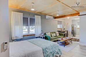 A modern bedroom with a bed, a green sofa, a small table, and a kitchenette in the background. - Luxe King Studio w/ Amazing View ~ Free Parking & WiFi (Memphis)
