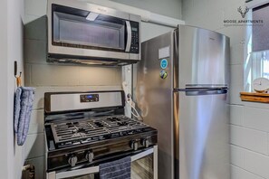 Una cocina equipada con microondas, estufa y refrigerador.