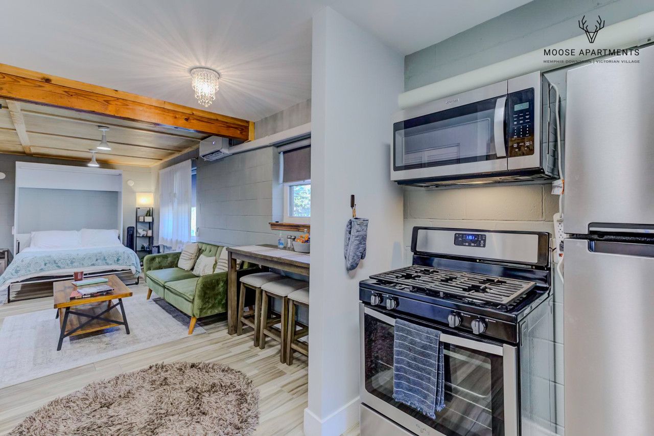 Un espacio habitable compacto con kitchenette, cama con cabecera, comedor y chimenea.