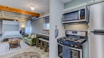 Un espacio habitable compacto con kitchenette, cama con cabecera, comedor y chimenea.
