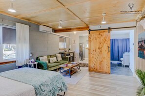 Un dormitorio acogedor con una cama, un sofá verde y una puerta de madera que da a un baño.