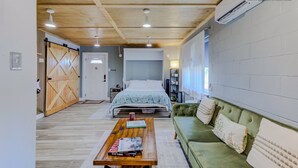 A modern bedroom with a bed, a green sofa, a wooden coffee table, and a large window. - Luxe King Studio w/ Amazing View ~ Free Parking & WiFi (Memphis)