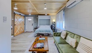 A modern bedroom with a bed, a green sofa, a wooden coffee table, and a large window. - Luxe King Studio w/ Amazing View ~ Free Parking & WiFi (Memphis)