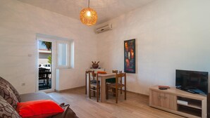 Ett kompakt bostadsutrymme med en matplats, en tv och en tavla på väggen.
