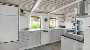 Een keuken met witte kasten, een roestvrijstalen afzuigkap en een raam met uitzicht op groen.
