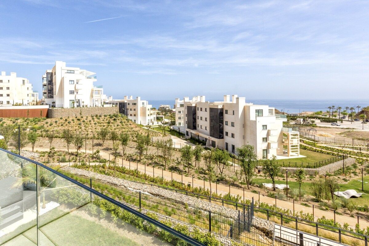 Ein Wohngebiet mit modernen Gebäuden, blauem Himmel und Blick auf das Meer.