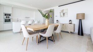 A modern kitchen with white cabinetry, a wooden dining table, and six chairs. - Panorama | pool - terrace - sea views (Fuengirola)