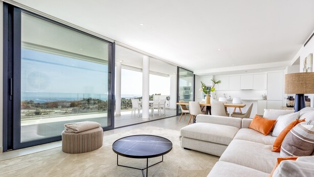 A modern living room with a large glass door leading to a balcony, a round coffee table, a sofa, and a dining area with a table and chairs. - Panorama | pool - terrace - sea views (Fuengirola)