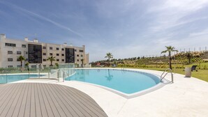 A modern hotel with a swimming pool, a wooden deck, and a view of the surrounding landscape. - Panorama | pool - terrace - sea views (Fuengirola)