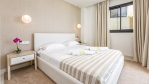 A neatly made bed with striped bedding, a bedside table with a lamp, and a window with curtains. - Panorama | pool - terrace - sea views (Fuengirola)