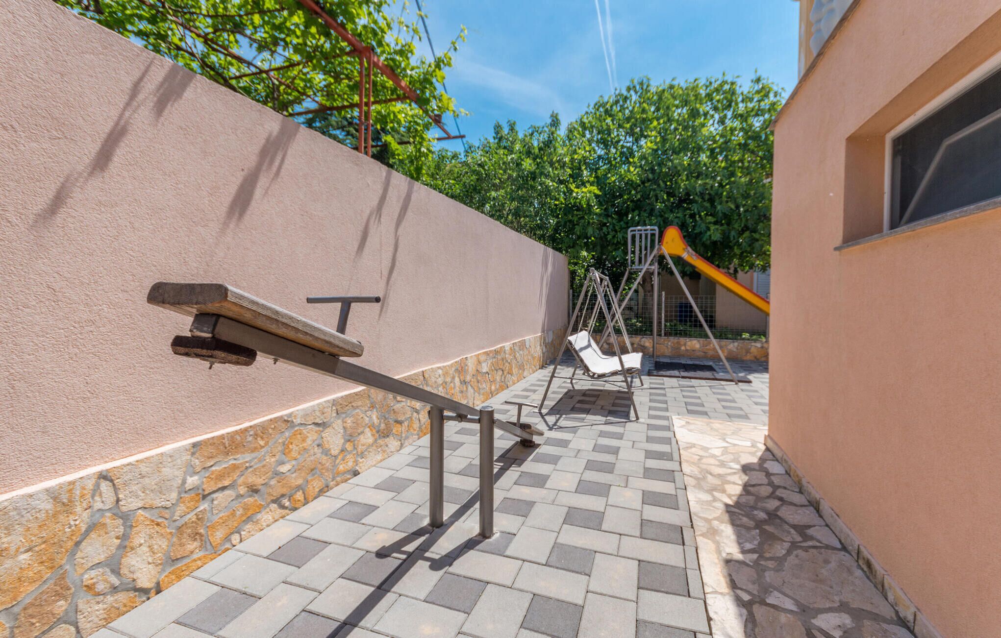 Une terrasse avec une balançoire, un banc et un espace de jeux équipé d’un toboggan.