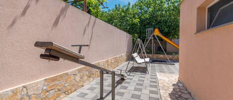 Une terrasse avec une balançoire, un banc et un espace de jeux équipé d’un toboggan.