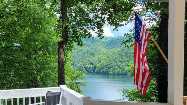 En træterrasse med gelænder, et bord og en stol, samt et amerikansk flag.