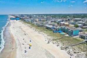 Uma vila costeira com praia, edifícios e calçadão demarcado.