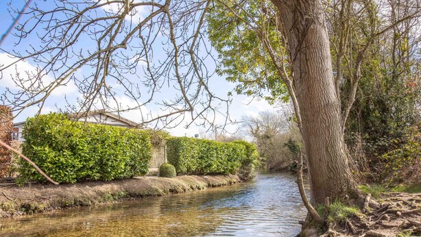 A narrow waterway flanked by dense greenery and a building with a traditional design. - Stunning Character 2bed Cottage in St Albans Wifi (St Albans)