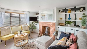 A living room with a fireplace, a sofa set, a coffee table, and a bookshelf. - Stunning Character 2bed Cottage in St Albans Wifi (St Albans)