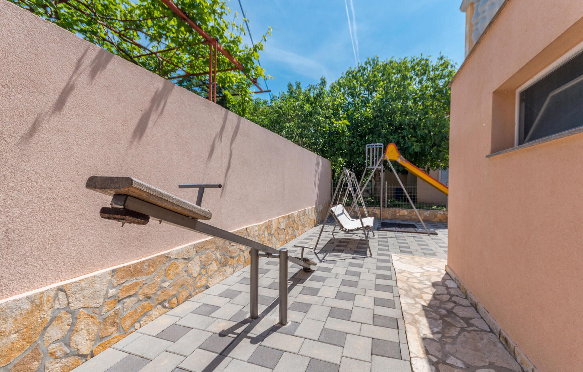 A patio area with a stone wall, a metal swing set, and a metal bench.