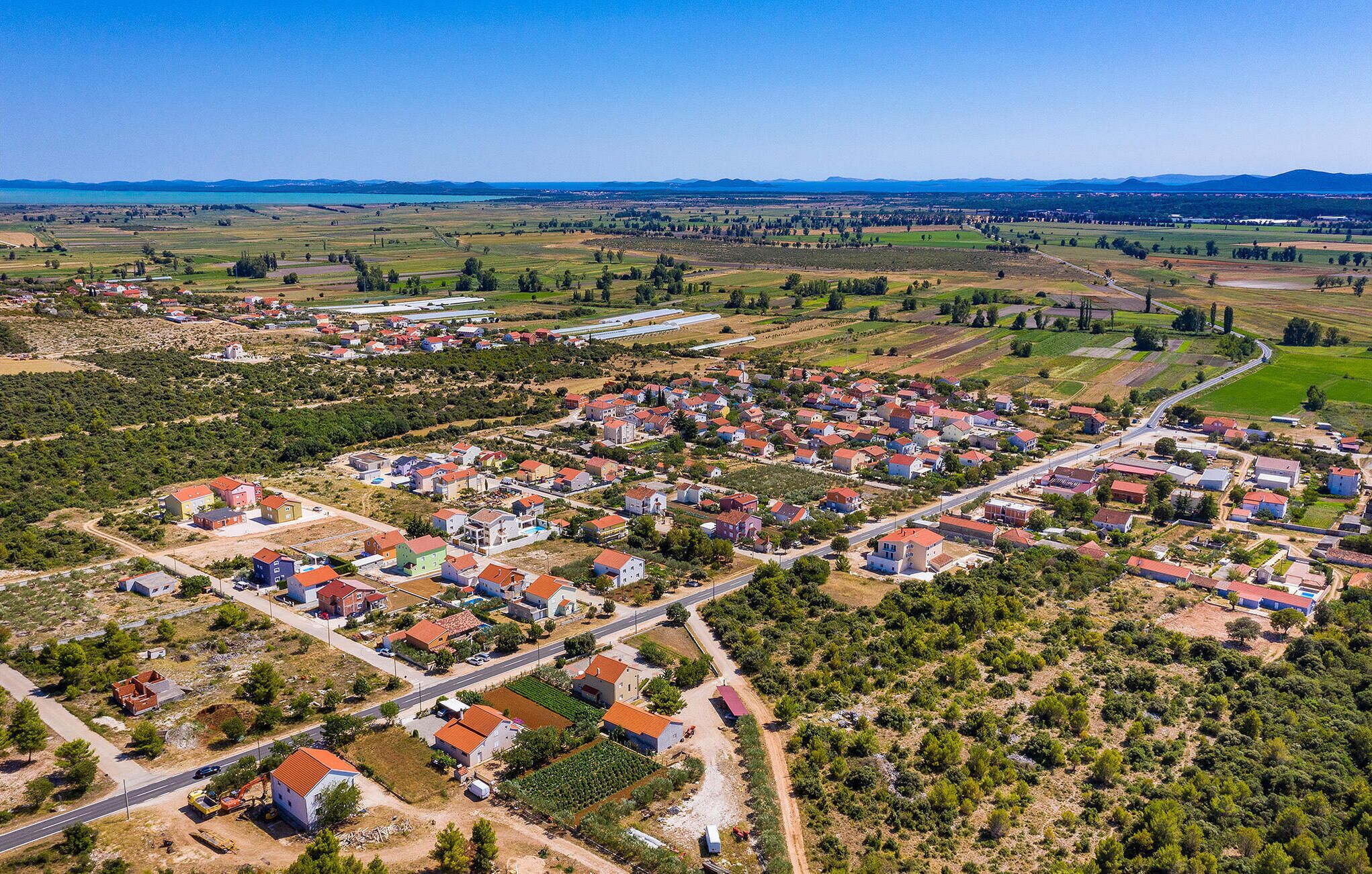 Luchtbeeld van een woongebied met huizen, wegen en velden.