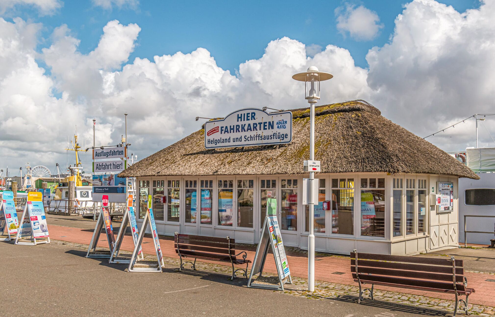 Een gebouw met rieten dak, met een bord waarop staat 'Hier Fahrkarten' en 'Helgoland und Schiffsausflüge'.