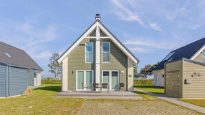 A two-story building with a gabled roof, a covered outdoor seating area, and a paved entrance. - Beautiful home in Büsum with sauna (Büsum)