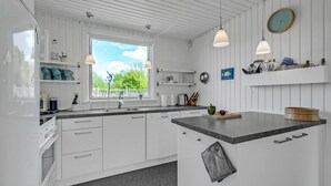 Eine moderne Küche mit weißen Schränken, einer Granit Arbeitsplatte und Pendelleuchten.
