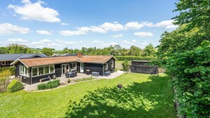 Ein modernes Haus mit geräumiger Terrasse, einem eingezäunten Garten und freiem Blick auf die umliegende Landschaft.