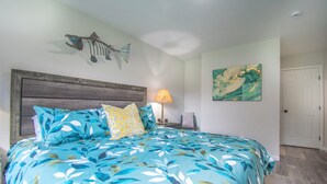 A bedroom with a bed, a nightstand, a lamp, a fish decoration, and a painting on the wall. - Entire home remodeled & 1 mile to Kenai River & 1/2 block to Peninsula Hospital (Soldotna)