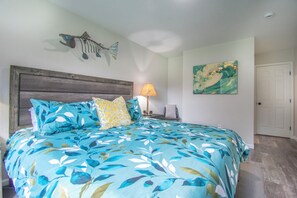 A bedroom with a bed, a nightstand, a lamp, a fish decoration, and a painting on the wall. - Entire home remodeled & 1 mile to Kenai River & 1/2 block to Peninsula Hospital (Soldotna)