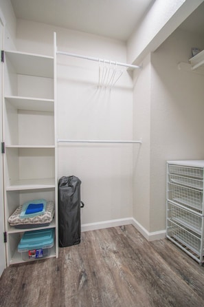 A walk-in closet with open shelves, a hanging rod, and a storage unit with bins. - Entire home remodeled & 1 mile to Kenai River & 1/2 block to Peninsula Hospital (Soldotna)