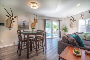 Un coin repas comprenant une table et des chaises, un canapé et des têtes d’antilopes décoratives accrochées aux murs.
