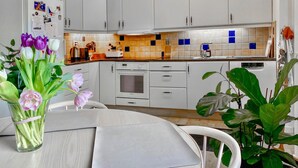 Eine moderne Küche mit weißen Schränken, einer gefliesten Spritzschutzwand und einem Essbereich mit Tisch und Stühlen.