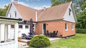 Ein zweistöckiges Haus mit rotem Ziegeldach, Ziegelaußenwand und einer kleinen Terrasse mit Gartenmöbeln.